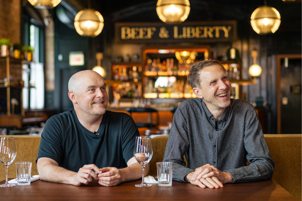 Founders Will and Hue smiling at a table in the Beef & Liberty room
