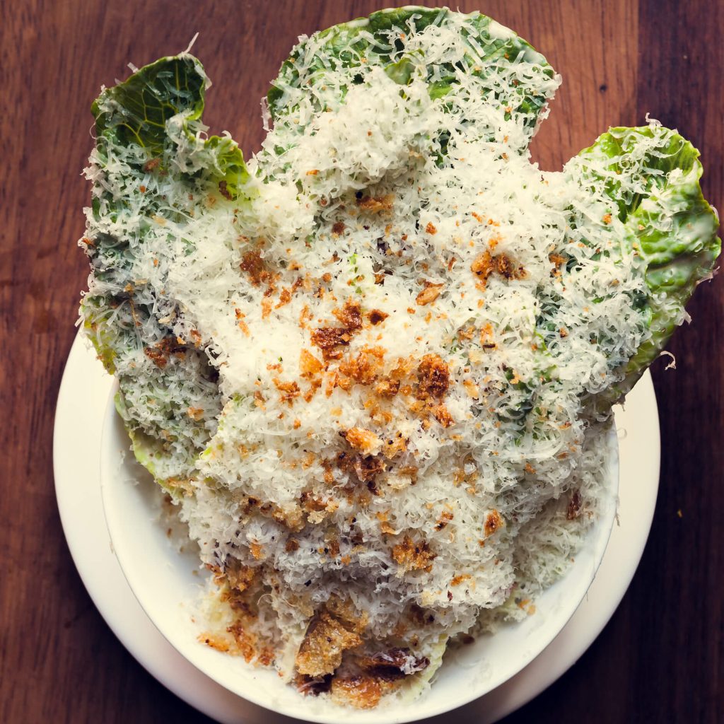 Hawksmoor Lunch Offerings 4 Bar bites and cocktails arranged on a polished wooden table in a lounge setting, featuring sliders, sausage rolls, Scotch eggs, grilled skewers, and martinis